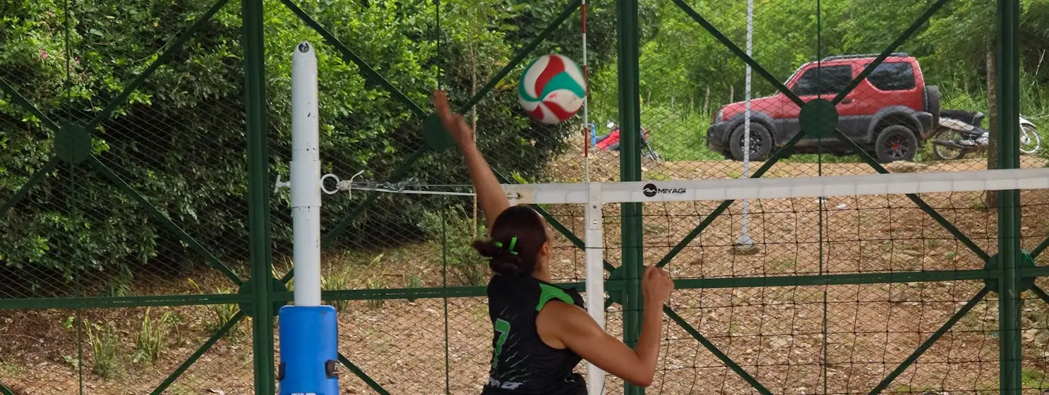 Deportista de voleibol en acción junto a la red de una cancha al aire libre